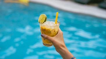 Viajero Hostels | Viajero Cali | Persona sosteniendo un coctel en el área de piscina de Viajero Cali