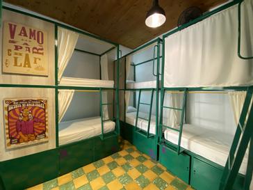 Viajero Hostels | Viajero Cali | Shared room with green metal bunk beds, personal lockers, and graphic art.