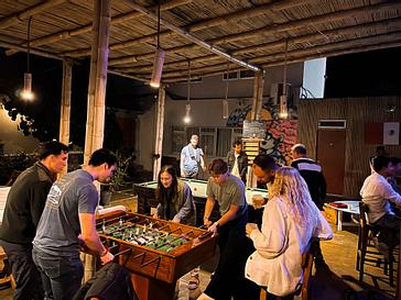 Viajero Hostels | Viajero Paracas Hostel | There are four people playing foosball at Viajero Kokopelli Paracas inside a crowded bar.
