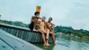 Viajero Hostels | Viajero Guatapé Hostel   | Amigos disfrutando de la tarde en el muelle con lago Viajero Hostels Guatapé, con vista al pueblo y las montañas