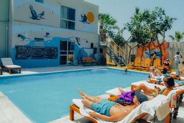 Viajero Hostels | Viajero Paracas Hostel | People sunbathing by the pool at Viajero Kokopelli Paracas.