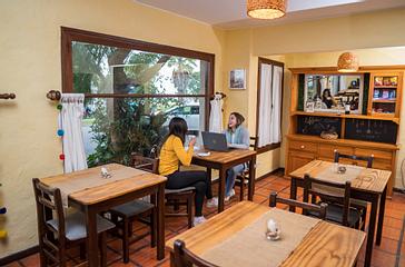 Viajero Hostels | Viajero Colonia Posada B&B | Amigas disfrutando de un café en la zona de comedor, mientras ríen y se sumergen en la cultura uruguaya en el hostal de colonia Viajero Hostels