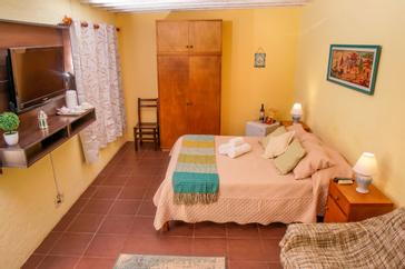 Viajero Hostels | Viajero Colonia Posada B&B | Habitación con privada con cama doble, televisión, mini refrigerador y sofá de viajero Hostels Colonia Posada.