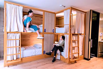 Viajero Hostels | Viajero Bogotá | Amigas disfrutando en las literas estilo cajon en madera en una habitación compartida de viajero