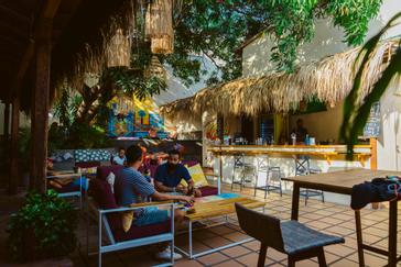 Viajero Hostels | Viajero Cartagena | Amigos pasando la tarde con una bebida en el área de piscina y bar con sofas coloridos de viajero hostel Cartagena dentro de la ciudad amurallada