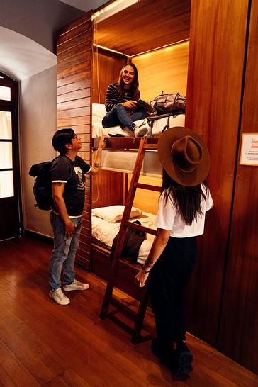 Viajero Hostels | Viajero Quito | Viajeros conociendo y compartiendo sus culturas en dormitorio compartido con camas estilo litera y cortina de privacidad en viajero Hostel Quito