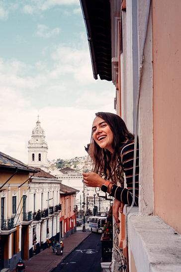 Viajero Hostels | Viajero Quito | Turista disfrutando de la vista de la ciudad con fondo a la iglesias más representativas de Ecuador desde su habitación en viajero hostel Quito