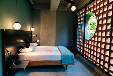 Viajero Hostels | Viajero Medellín | Habitación privada con cama doble, cabecero ancho, enchufe cerca a pared, mesitas de noche, entrada de luz natural, toallas y decoración
