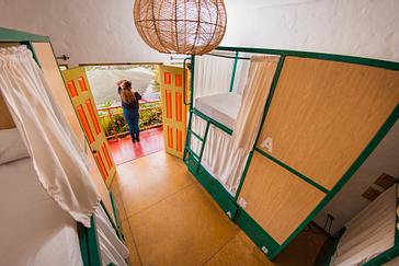 Viajero Hostels | Viajero Salento | Persona de pie en frente de la entrada de un dormitorio compartido con camas estilos camarote en Viajero Hostels Salento