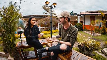 Viajero Hostels | Viajero Salento | Una pareja sentada en el espacio libre durante su Hospedaje en Salento en Viajero Hostels, mientras disfrutan un café