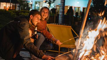 Viajero Hostels | Viajero Salento | Pareja de turistas disfrutando de la experiencia de fogata en la noche, azando malvaviscos en el viajero hostel Salento en la zona cafetera del país