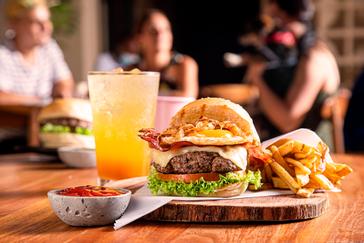 Viajero Hostels | Viajero Santa Marta | Menú de almuerzo en viajero hostel Santa Marta de hamburguesa, papas fritas, salsa y soda frutal servido en vajilla de madera y piedra