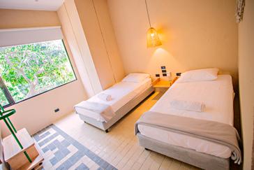 Viajero Hostels | Viajero Santa Marta | Habitación privada para dos personas con dos camas individuales, aire acondicionado, ventilador y vista a naturaleza de Viajero Hostel Cartagena