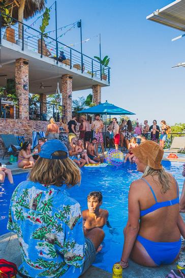 Viajero Hostels | Viajero Sayulita | Friends, tourists getting to know each other while spending the afternoon at the pool with a terrace offering a great view at the hostel in Sayulita.