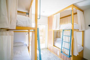 Viajero Hostels | Viajero Sayulita | Shared dormitory for four people with bunk beds featuring privacy curtains, personal lockers, and a balcony at Viajero Hostels Sayulita.