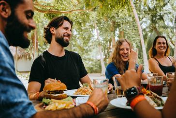 Viajero Hostels | Viajero Tayrona | Grupo de amigos disfrutando y compartiendo de una comida variada al aíre libre en medio de la naturaleza en viajero hostel Tayrona