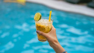 Viajero Hostels | Viajero Cali | Person holding a cocktail in the pool area of Viajero Cali.