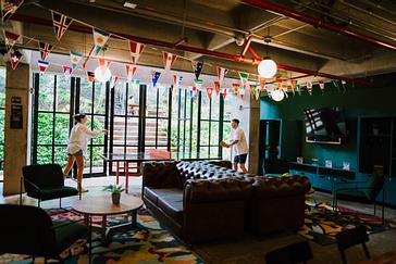 Viajero Hostels | Viajero Medellín | Amigos jugando ping pong en la sala social del hostel en el Poblado, Medellín con vista de la ciudad y terraza natural