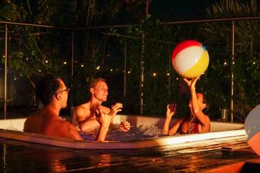 Viajero Hostels | Viajero Medellín | Amigos pasando la noche en el jacuzzi mientras participan del juego con pelota en la terraza con vista de Medellín y bar en Viajero hostels
